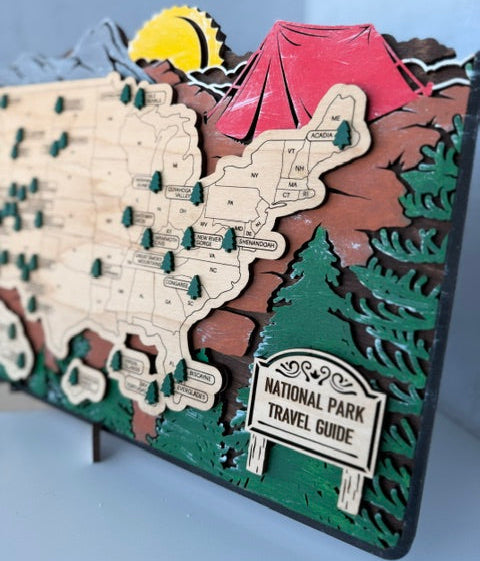 A 3D wooden National Parks travel guide map of the United States, featuring raised states, pine trees, a red tent, a yellow sun, and a 'National Park Travel Guide' sign on a light blue background.