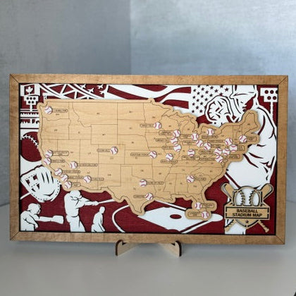A rectangular wooden baseball-themed map plaque of the United States, featuring a scratched wooden map of the country, red and white illustrations of baseball players, and a small gold-toned plaque at the bottom right, displayed on a small stand.